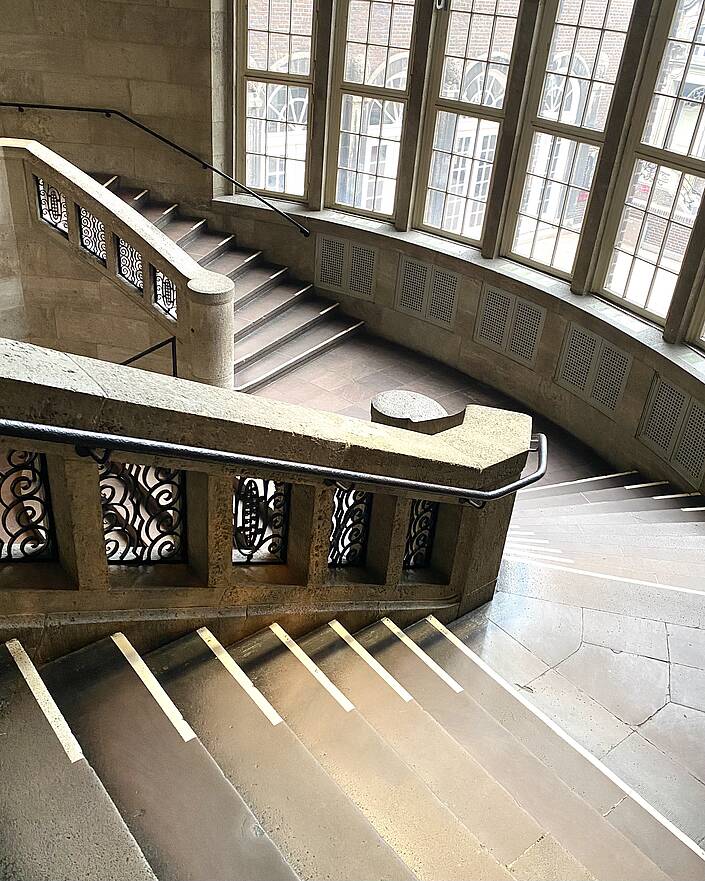 Treppenhaus von oben mit historischer Fensterfront im Hintergrund